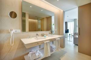 Badezimmer im Hipotels Gran Playa de Palma mit Doppelwaschbecken, Spiegel und Handtüchern.