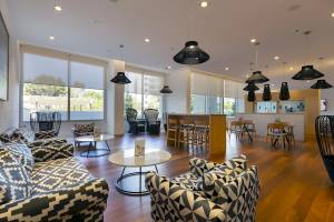 Innenbereich der Lobby im Hipotels Gran Playa de Palma mit modernen Möbeln, Holzböden und großen Fenstern.