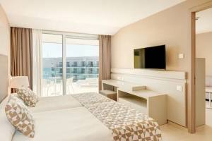 Ein Hotelzimmer mit Doppelbett, Fernseher, Schreibtisch und Meerblick.