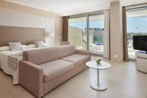 Suite Zimmer im Hipotels Gran Playa de Palma mit Bett, Sofa, Tisch und Fernseher.