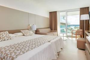 Schlafzimmer im Hipotels Gran Playa de Palma mit zwei Betten, einem Sofa und einem Tisch mit Blick auf das Meer.
