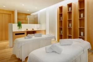 Wellness-Bereich im Hipotels Gran Playa de Palma mit zwei weißen Massagetischen und Holzschränken.