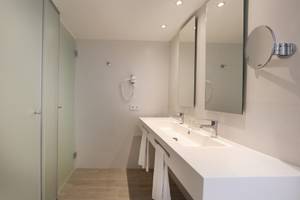 Badezimmer im Iberostar Playa de Muro mit Dusche, Spiegeln und Waschbecken.