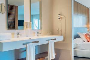 Innenansicht eines Hotelzimmers im Iberostar Playa de Muro, mit Blick auf ein modernes Badezimmer und ein gemütliches Bett.