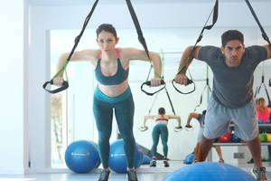 Fitness Workout im Hotel Iberostar Playa de Muro mit einer Frau und einem Mann, die an Zugbändern ziehen.