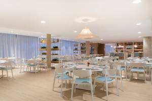 Innenraum des Restaurants im Iberostar Playa de Muro Hotel mit weißen Tischen und Stühlen.