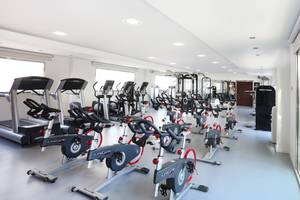Fitnessraum im Iberostar Playa de Muro mit verschiedenen Trainingsgeräten wie Laufbändern und Spinrädern.