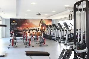 Fitnessstudio im Iberostar Playa de Muro mit einer Reihe von Spinrädern und Laufbändern.
