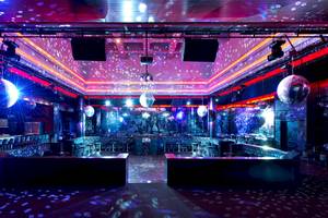 Disco-Saal im Gloria Serenity Resort mit lila und blauer Beleuchtung, Spiegelkugeln und Bar.