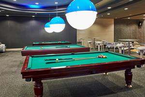 Zwei Billardtische im Hotellobby des Gloria Serenity Resort mit blauen Leuchten an der Decke.