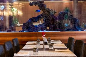 Restauranttisch vor einem großen Aquarium mit Fischen und Pflanzen im Gloria Serenity Resort.