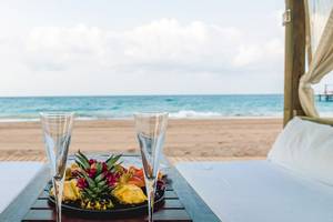 Zwei Liegesessel am Strand mit Gläsern und einer Obstplatte.