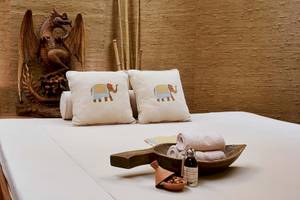 Bett im Gloria Golf Resort Spa mit weißen Laken, zwei Kissen mit Elefantenmuster und einem Holztablett mit Gegenständen.