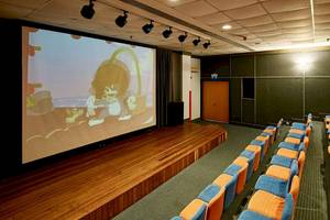Kinosaal im Gloria Golf Resort mit leeren Bänken und laufendem Film auf der Leinwand.