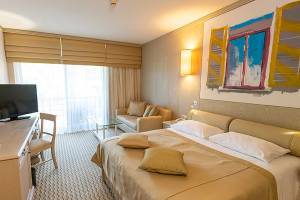 Hotelzimmer im Gloria Golf Resort mit Doppelbett, Fernseher, Sofa und Couchtisch.
