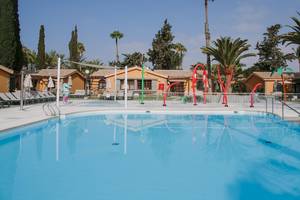 Außenpool im Suites & Villas By Dunas Hotel mit bunten Spielgeräten und Sonnenschirmen.