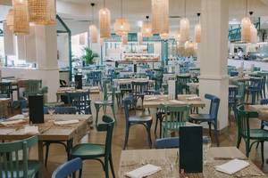 Innenansicht des Restaurants im Hotel Suites & Villas By Dunas mit blauen Stühlen und Holztischen.