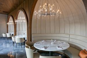 Innenansicht des Restaurants Titanic Luxury Collection Bodrum mit weißen Tischen, Stühlen und eleganten Leuchten.