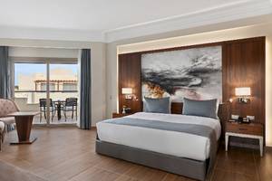 Innenansicht eines Zimmers im Xanadu Makadi Bay Hotel mit Bett, Sesseln und Terrassentür.