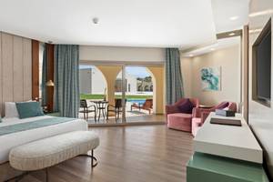 Innenansicht eines Hotelzimmers im Xanadu Makadi Bay mit Doppelbett, Sitzbereich und Terrassentür.