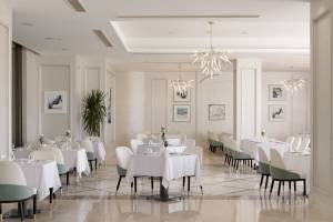 Innenansicht des Restaurants im Xanadu Makadi Bay Hotel mit gedeckten Tischen und eleganten Kronleuchtern.