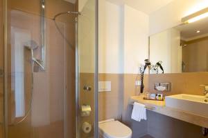 Badezimmer im Aimia Hotel mit Dusche, Toilette und Waschbecken.