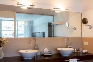 Badezimmer im Aimia Hotel mit zwei Waschbecken und Spiegeln.