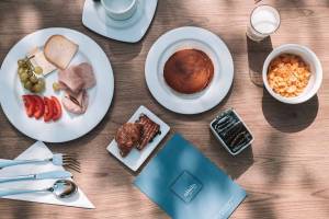 Frühstücksbuffet im Aimia Hotel mit verschiedenen Gerichten und Getränken auf einem Holztisch.