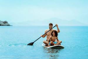 Ein Vater und sein Sohn paddeln auf einem SUP-Board im Meer.