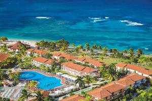 Oberflächenansicht des Memories Jibacoa Resorts mit Pool, Gebäuden und Meer im Hintergrund.