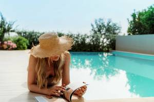 Eine Dame liest ein Buch am Pool im Ikos Dassia Hotel.