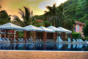 Poolbereich des Memories Jibacoa Resorts mit weißen Sonnenschirmen und Liegestühlen.