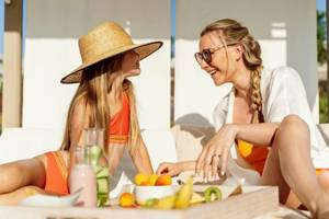Zwei Frauen im Ikos Dassia Hotel sitzen am Tisch mit Früchten und Getränken.