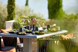 Terrasse mit Speisen im Ikos Dassia, Gerichte auf dem Tisch, Blumenvase und Kerzen.