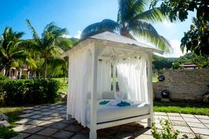 Weißer Liegestuhl im Freien im Memories Jibacoa Resort mit Vorhängen und Dekorententen.