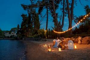 Romantisches Essen am Strand bei Abend mit Kerzen und Lichterketten.