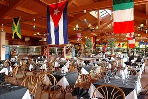 Innenbereich des Memories Jibacoa Resorts mit gedeckten Tischen und internationalen Flaggen.
