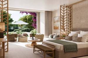 Innenansicht eines Zimmers im Ikos Odisia Hotel mit großem Bett, Sofas, Tisch und Pflanzen.