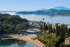 Luftaufnahme des Ikos Odisia Hotels am See mit Bergen im Hintergrund.