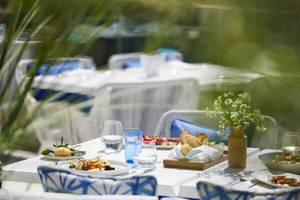 Außenterrasse des Ikos Odisia Hotels mit gedeckten Tischen und Stühlen, Tellern mit Essen und Getränken.