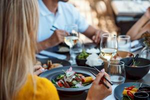 Ein Paar isst im Restaurant Ikos Olivia mit verschiedenen Gerichten und Weingläsern.
