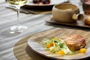 Speisen im Ikos Porto Petro, darunter ein Gericht mit Fleisch und Gemüse auf einem Teller.