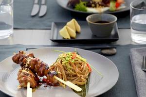 Ein Teller mit gegrilltem Fleisch und Nudeln im Ikos Porto Petro Hotel.