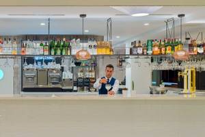 Die Bar Theta im H10 Casa del Mar Hotel mit gut gekleideten Barkeepern und einer Auswahl an Getränken.