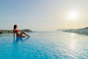 Frau im roten Bikini am Pool des H10 Casa del Mar, das Meer und die Stadt im Hintergrund