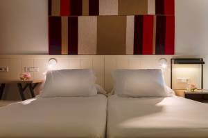 Doppelbett-Zimmer im H10 Casa del Mar Hotel mit zwei weißen Kissen und einer farbigen Wand.
