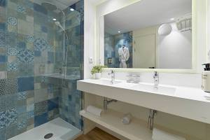 Badezimmer des H10 Casa del Mar mit blauen gemusterten Fliesen und einer großen Dusche.