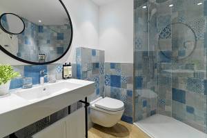 Badezimmer im H10 Casa del Mar Hotel mit blauen und grauen Fliesen, Dusche und Toilette.