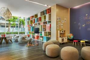 Kinderzimmer im FIVE Palm Jumeirah mit bunten Regalen, Spielsachen, Sofas und einer Wand mit Zeichnungen.