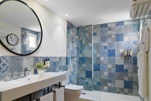 Das Badezimmer des H10 Casa del Mar Hotels mit blauen und grauen Fliesen, einem Spiegel, einem Waschbecken, einer Toilette und einer Dusche.